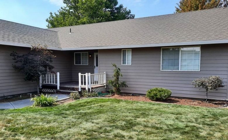 A residential home with a small front lawn that has been recently mowed by Telos Lawn Care. The home is lined with a small landscape bed with pruned shrubs and small trees.