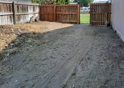 A sandy back yard after being cleaned up. All clippings, debris, and weeds have been cleaned up and hauled away.